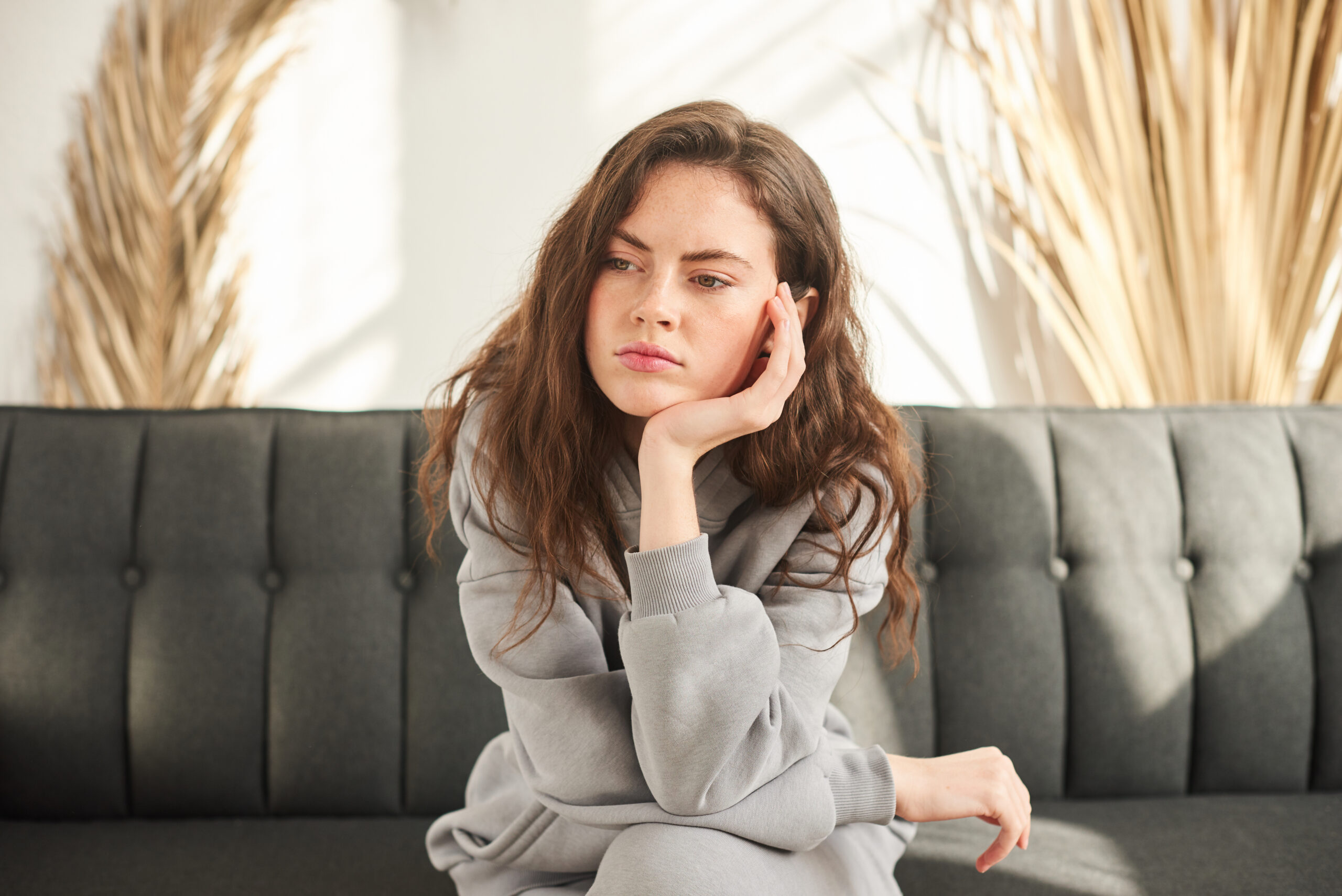 bored and sad woman sitting on couch with no mood and prop up head with hand